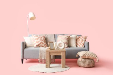 Rahat gri kanepe, ahşap sehpa ve pembe arka planda halı.