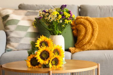 Oturma odasındaki sehpada rahat bir kanepe ve yabani çiçekler. Yakın çekim.