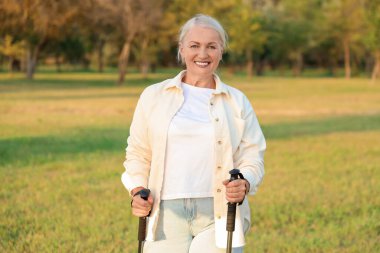 Olgun kadın antrenmanı parkta sırıklarla, yakın plan.