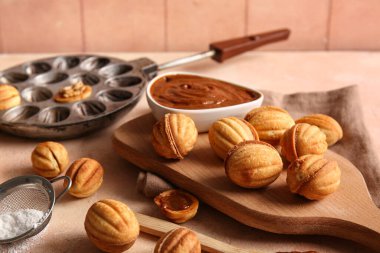 Lezzetli ceviz şekilli kurabiyelerle ahşap tahta tahta ve renkli masada haşlanmış süt.