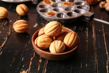 Koyu ahşap masada kaynamış konsantre sütle ceviz şeklinde kurabiyeler.