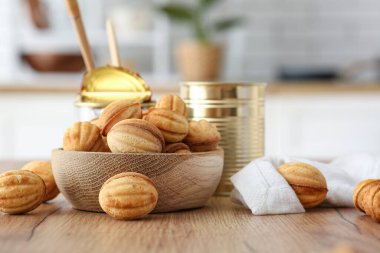 Bir kase lezzetli ceviz şekilli kurabiye ve ahşap masada kaynatılmış süt.