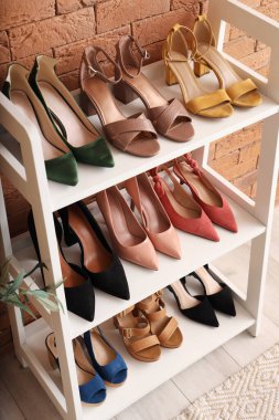Odadaki tuğla duvarın yanındaki raflarda şık kadın ayakkabıları