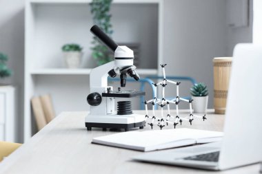 Genç kızın odasındaki masada moleküler modelle modern mikroskop, yakın plan.