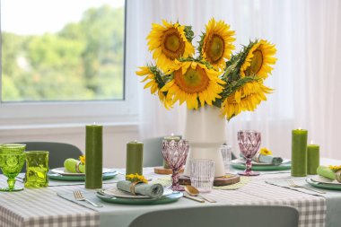 Odadaki yemek masasında vazo ve ayçiçeği.