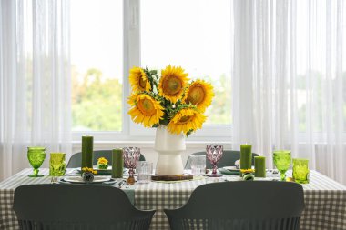 Odadaki yemek masasında vazo ve ayçiçeği.