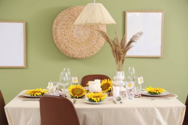 Yeşil duvarın yanındaki tabakta ayçiçekleri olan güzel bir masa.