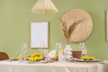 Yeşil duvarın yanında ayçiçekleri olan masa ayarı