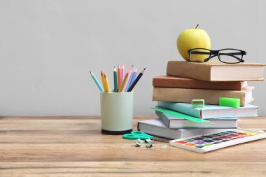 Gözlüklü ve elmalı farklı kırtasiye seti gri duvara karşı ahşap masada.