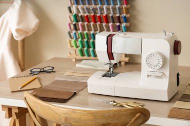 Atölyedeki terzi masasında kumaş örnekleri olan dikiş makinesi.