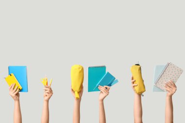 Beyaz arka planda farklı okul malzemelerine sahip kadın eller.