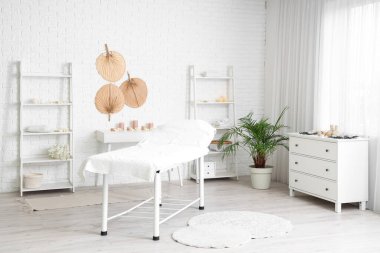 Koltuğu, mumları ve beyaz mobilyaları olan bir spa salonu.