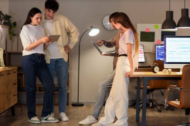 Programcılardan oluşan bir ekip gece ofiste aletlerle çalışıyor.