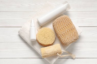 Hafif ahşap arka planda banyo malzemeleri ve kozmetik ürünleri ile kompozisyon