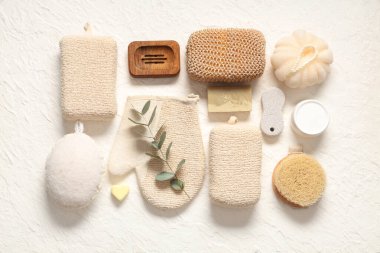 Farklı banyo süngerleri, masaj fırçaları ve hafif arka planda kozmetik ürünleri içeren kompozisyon