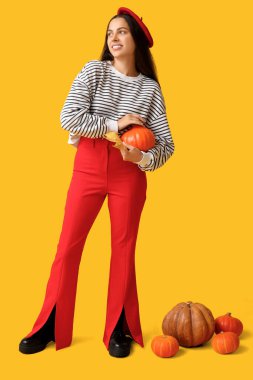 Taze balkabakları ve sarı arka planda sonbahar yaprağı olan zarif genç bir kadın.