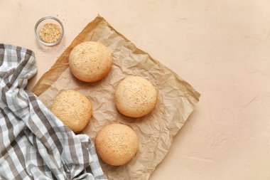 Bej arka planda susam tohumlu taze çörekler pişirme kağıdı.