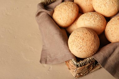 Kahverengi zemin üzerinde susam tohumları olan bir sepet taze çörek.