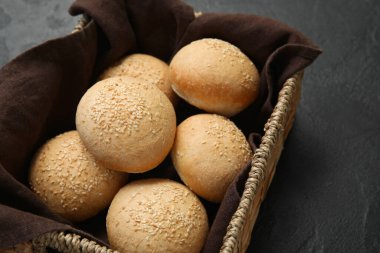 Siyah zemin üzerinde susam tohumları olan bir sepet taze çörek.