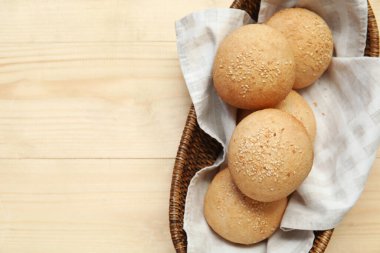 Tahta arka planda susam tohumlu bir tabak taze çörek.