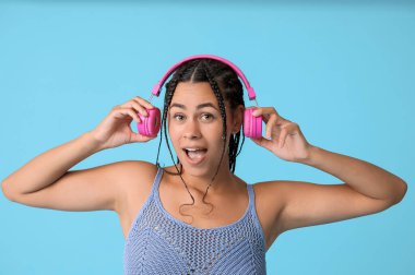 Duygusal Afro-Amerikalı kadın mavi arka planda müzik dinliyor.