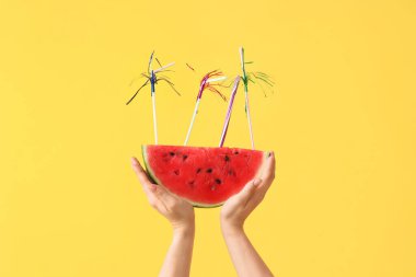 Tatlı karpuz dilimli kadın elleri ve sarı arka planda pipetler