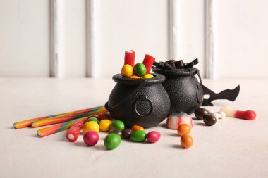 Işık masasında Cadılar Bayramı için farklı ikramları olan tencereler.