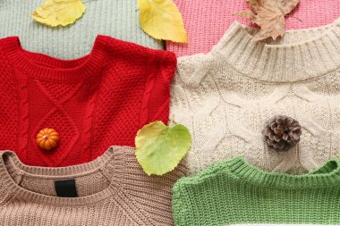 Farklı sıcak süveterler ve sonbahar yapraklarıyla kompozisyon, yakın plan.