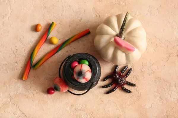 stock image Pot with sweet treats and pumpkin for Halloween on color background