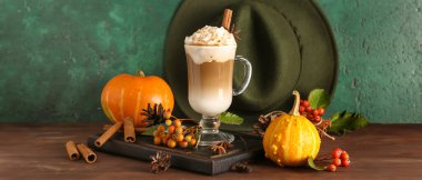 Sonbahar kompozisyonu, cam bardak ve ahşap masada balkabaklı latte.