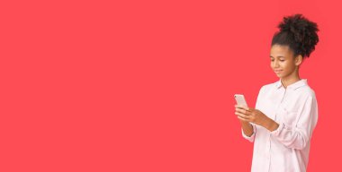 Kırmızı arka planda cep telefonu olan Afro-Amerikalı genç bir kız. Mesaj için yeri var.