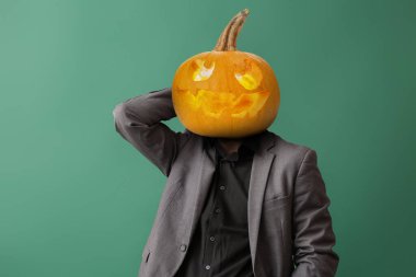 Yeşil arka planda kafası yerine balkabağı olan bir iş adamı.