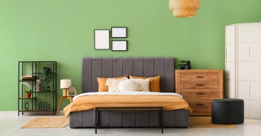 Rahat yatak, askı ve ahşap çekmeceler şık bir yatak odasında.