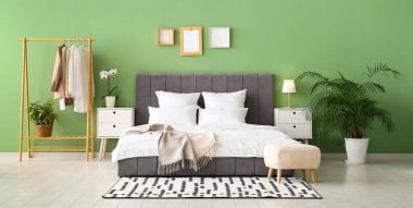 Rahat yatak, elbise askısı ve şık yatak odasındaki komodinlerin yanında.