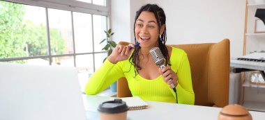 Stüdyoda mikrofon kaydı olan genç bir Afro-Amerikalı kadın.