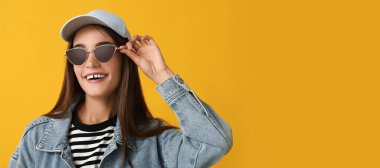 Sarı arka planda şık güneş gözlüklü genç bir kadın, mesaj için yeri var.