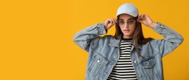 Sarı arka planda şık güneş gözlüklü genç bir kadın, mesaj için yeri var.