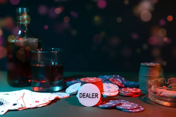 stock image Poker chips, cards and alcohol on table against dark background