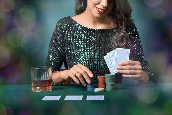 Young woman at poker table with cards, chips and glass of whiskey 