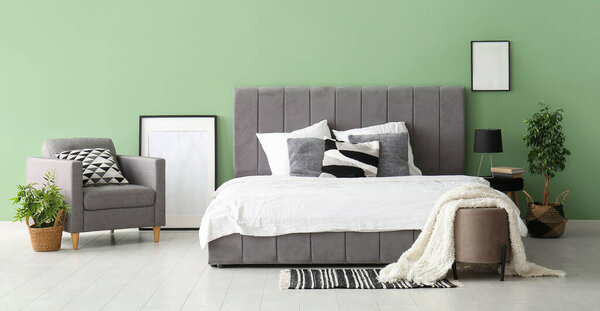 Удобная кровать и кресло в стильной спальне
