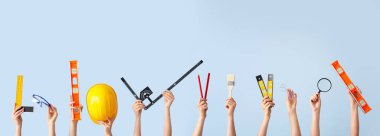 Açık mavi arka planda mimarın malzemeleriyle birçok el.