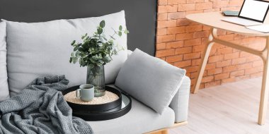 Okaliptüs dallı vazo ve odadaki kanepede bir fincan çay.