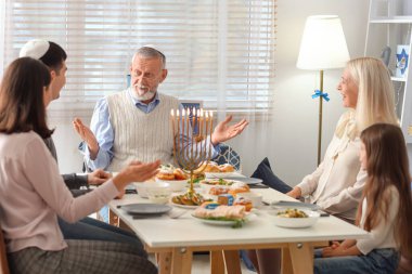 Olgun bir adam Hanuka 'da aile yemeği yiyor.