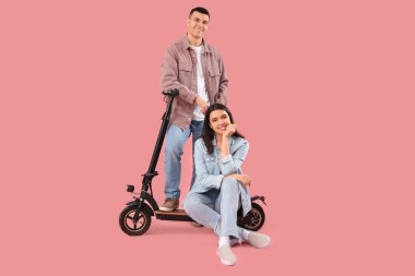 Pembe arka planda elektrikli scooter kullanan genç bir çift.