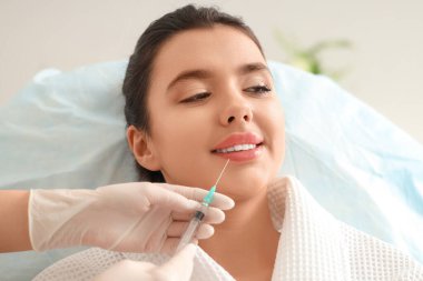 Genç bir kadın güzellik salonunda dudak iğnesi yaptırıyor.