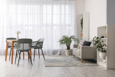 Masası, sandalyeleri, kanepesi, çiçekleri ve raf ünitesi olan modern oturma odasının içinde.