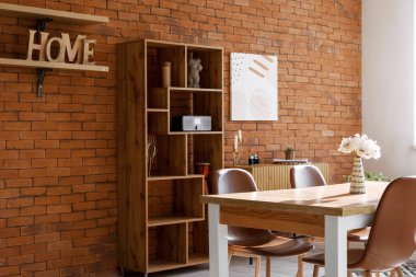 Masası, sandalyeleri ve raf ünitesi olan bir çatı katı tarzı oturma odası.