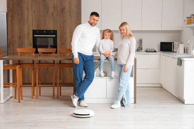 Mutfakta elektrikli süpürgesi olan mutlu bir aile.