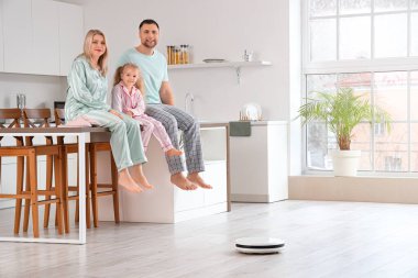 Mutfakta yerde elektrikli süpürgesi olan mutlu bir aile.