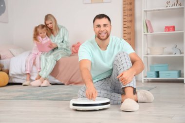 Çocukların yatak odasında elektrikli süpürgeyle mutlu bir baba.